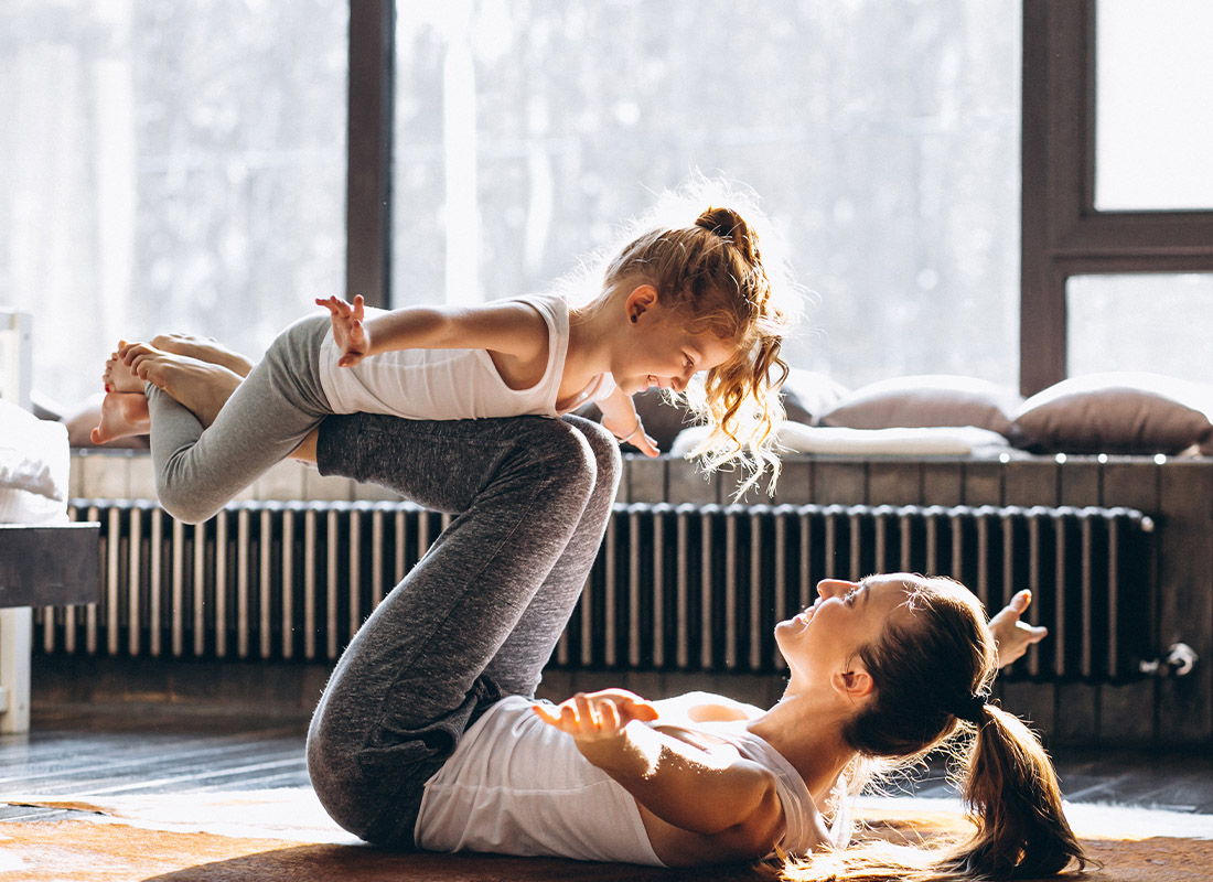 Personal Insurance - Mother and Daughter Having a Yoga Session at Home in the Family Living Room